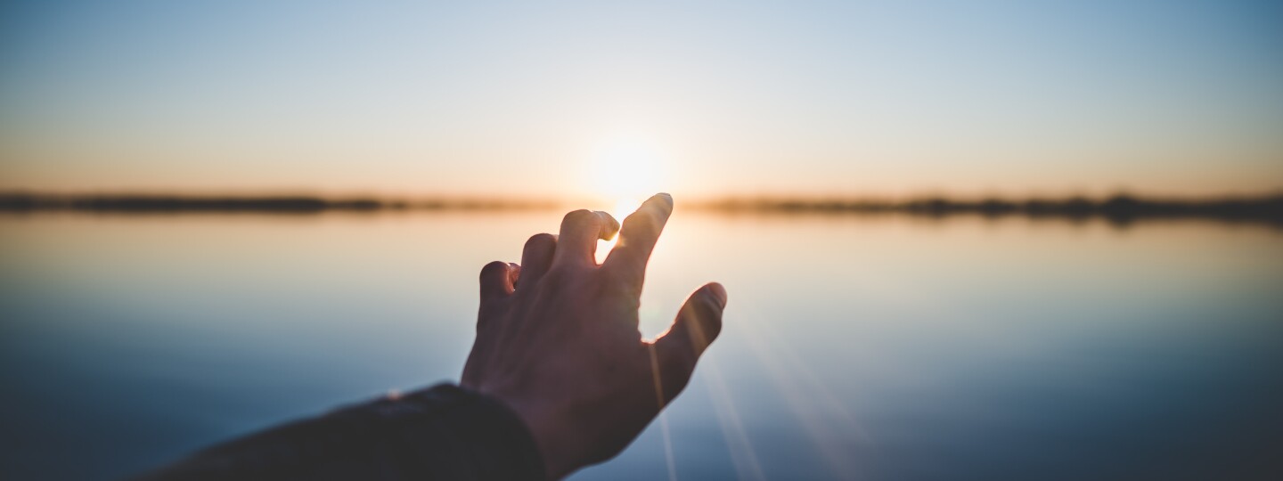 Hand reaching the sunset