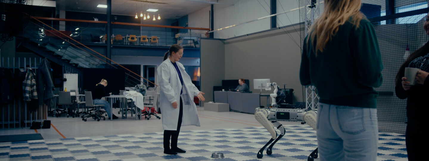 Opiskelija robottikoiran kanssa laboratoriossa.