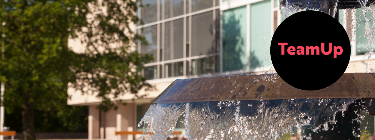 Kesäinen yliopistonmäen suihkulähde lähikuvassa aurinkoisella ilmalla. Kuvan päällä tapahtuman tekstitunnus TeamUp