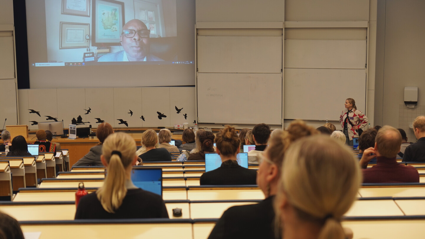 Audience watching a speaker from a screen in a lecture hall