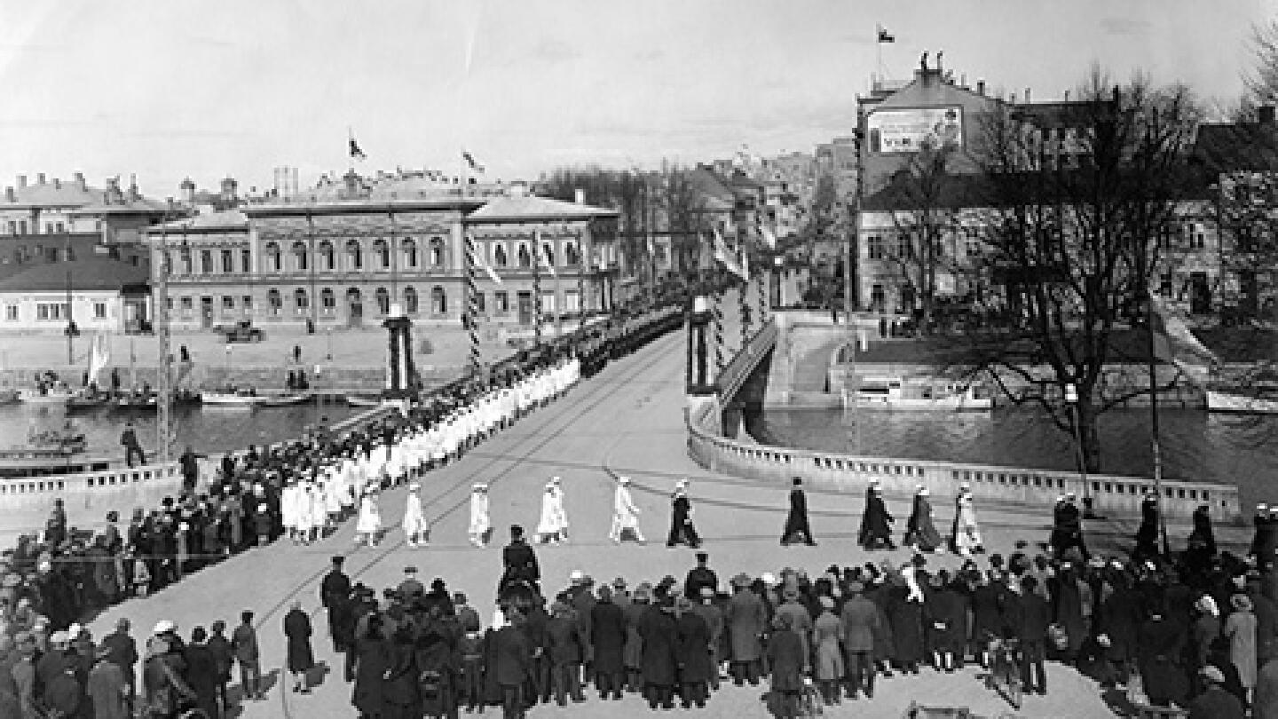 Turun Yliopiston vihkiäisjuhla ja ensimmäinen promootio 12. toukokuuta 1927. Yliopistollinen kulkue ylittämässä Auran siltaa. Kulkue on kääntynyt Itäiselle Rantakadulle.