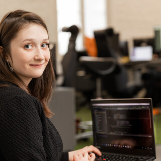 A woman with a laptop looking at the camera